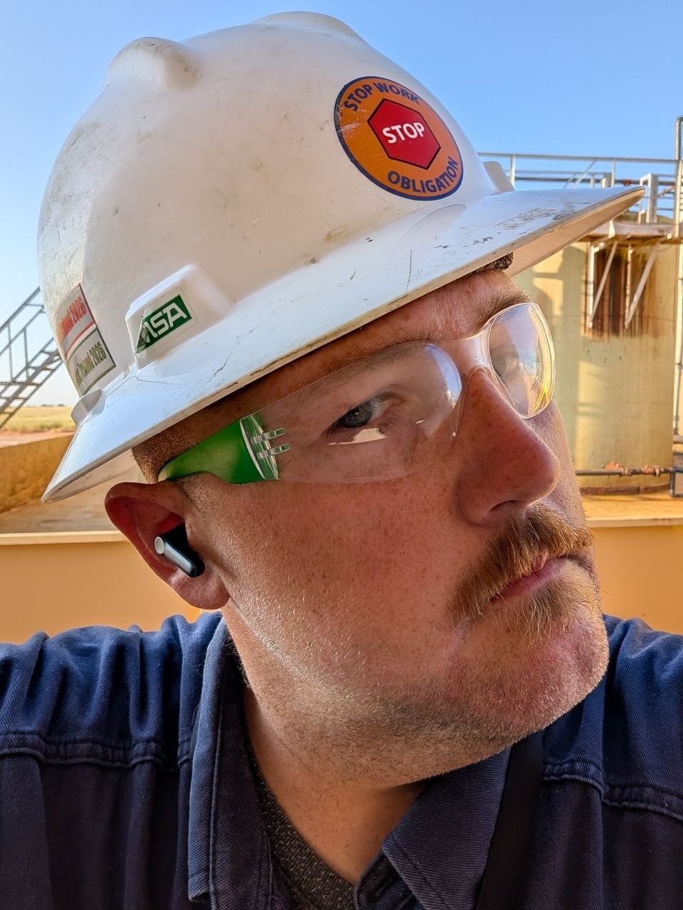 Founder of Saxon South in a hard hat and safety glasses at a tank battery